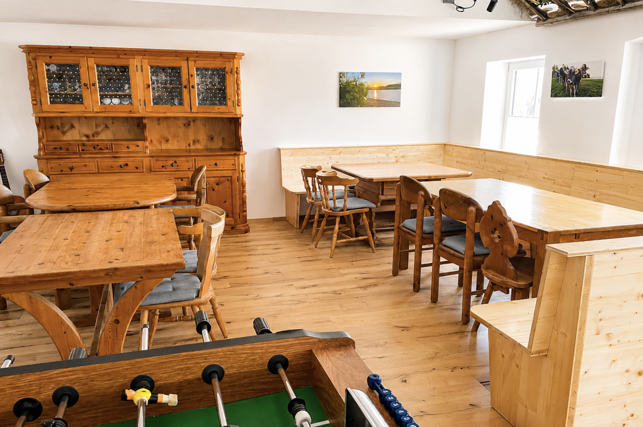 Großer Aufenthaltsraum im Gästehaus Alte Käskucha im Allgäu mit Kicker, Sitzbereichen und Holzinterieur nahe Rottachsee